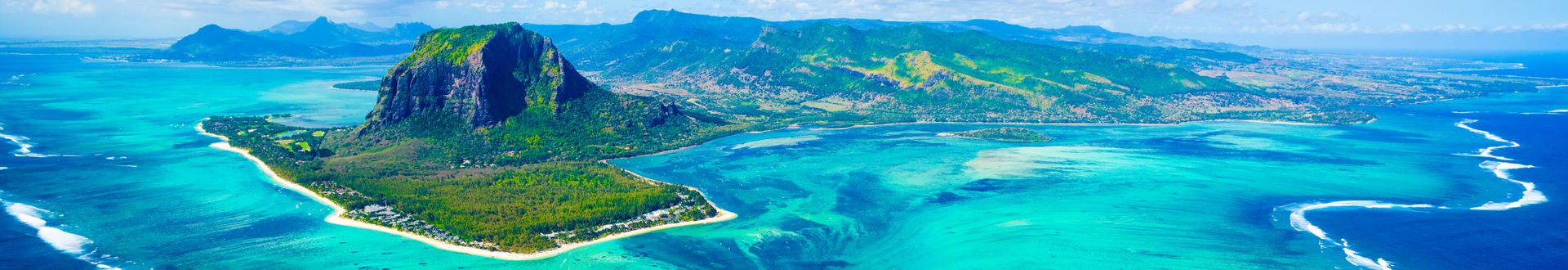 Luftaufnahme von Mauritius mit grün bewachsenen Bergen, türkisfarbenem Wasser und weißen Sandstränden.