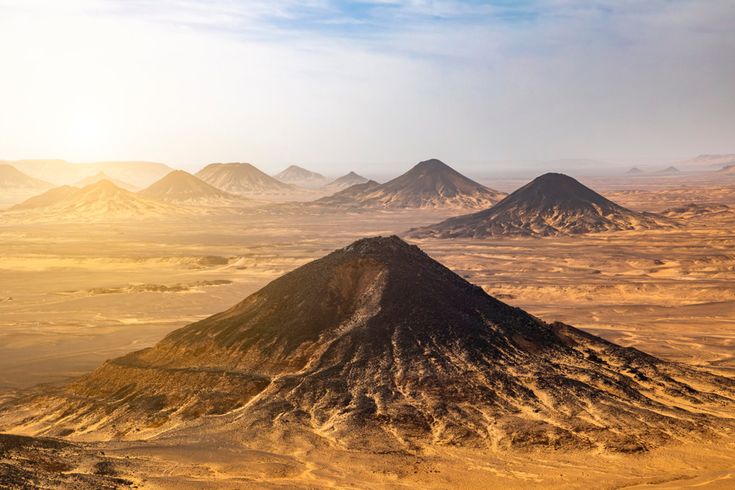 Schwarze Wüste in Ägypten mit markanten dunklen Vulkanhügeln inmitten goldener Sahara-Sanddünen