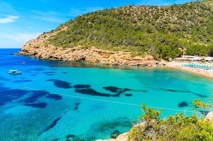 Bucht Cala Benirràs auf Ibiza mit türkisfarbenem Wasser, Felsen und Strandbesuchern