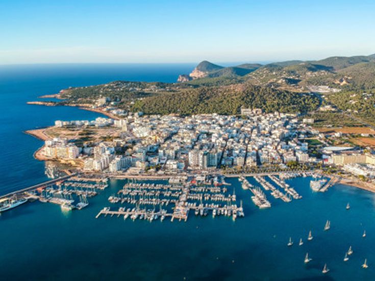 Luftaufnahme des Hafens von San Antonio auf Ibiza mit zahlreichen Segelbooten, Yachten und dicht bebauter Küstenstadt