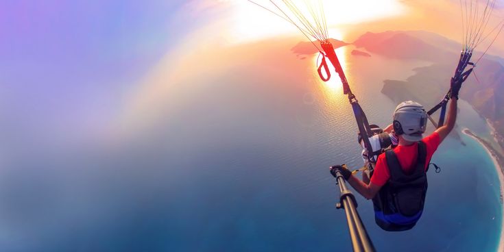 Paraglider fliegt über der türkischen Küste bei Sonnenuntergang, Blick auf blaues Meer und Inseln aus der Luft