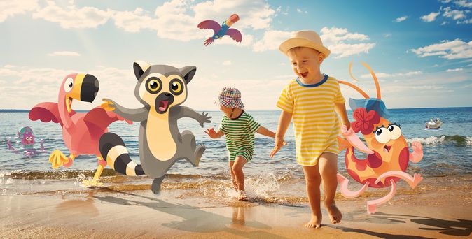 Zwei Kinder laufen am Strand am Meer entlang, begleitet von animierten Figuren eines Flamingos, eines Lemuren und eines Oktopus mit Blume