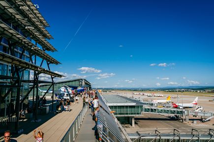 Besucherterrasse am Flughafen Stuttgart mit Aussicht auf Start- und Landebahnen, Flugzeuge an den Gates sowie Besucher entlang der Panoramaplattform