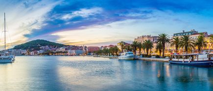 Küste von Split in Mitteldalmatien, Kroatien, mit historischer Altstadt, Hafen und Palmen bei Sonnenuntergang