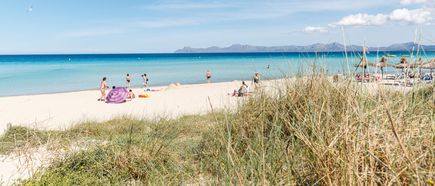 Strand von Playa de Muro auf Mallorca mit feinem Sand, türkisblauem Meer und Urlaubern beim Sonnen und Baden