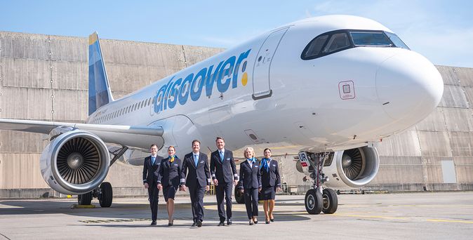 Crew von Discover Airlines vor einem Airbus A320 auf dem Vorfeld, mit gut sichtbarem Discover-Airlines-Logo am Flugzeugrumpf