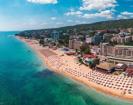 Luftaufnahme eines breiten Sandstrands in Varna mit vielen Sonnenschirmen und Hotels entlang der Küste