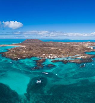 Luftaufnahme der Insel Isla de Lobos vor Fuerteventura mit türkisfarbenem Wasser und wolkigem Himmel.