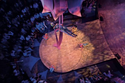 Artistik-Show im Theatrium der AIDAbella mit einer Akrobatin, die in pinken Tüchern hoch über der Bühne performt, eindrucksvoll beleuchtet durch Scheinwerfer