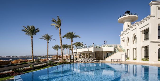 Außenbereich des SUNRISE Remal Beach mit großem Pool, Palmen, heller Hotelarchitektur und Blick auf das Rote Meer.