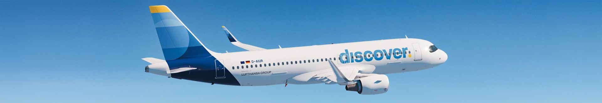 Airbus A320-200 von Discover Airlines mit blau-gelbem Leitwerk im Flug vor blauem Himmel, einschließlich gut sichtbarem Discover-Schriftzug, Lufthansa Group Kennzeichnung und Flugzeugregistrierung auf dem Rumpf.