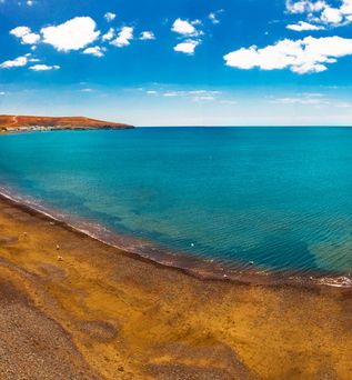 Küste am blauen Meer unter leicht bewölktem Himmel