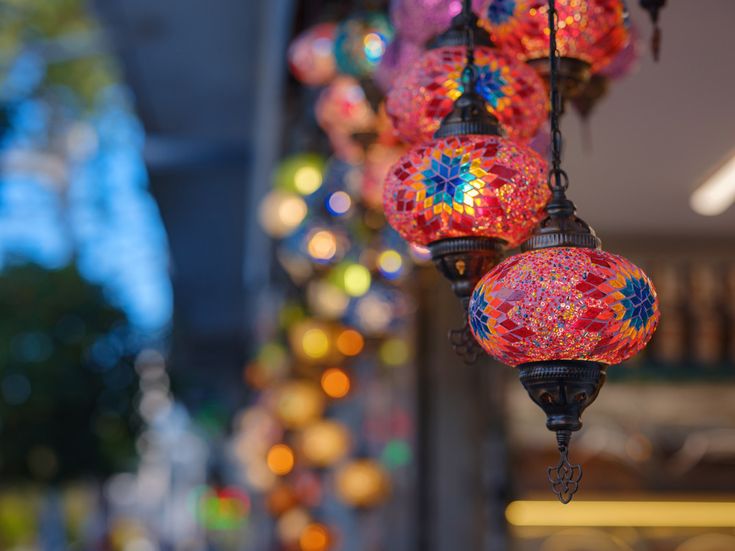 Bunte orientalische Mosaiklampen hängen in einer Reihe und leuchten mit kräftigen Farben