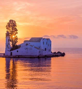 Kirchengebäude auf kleiner Insel bei Sonnenuntergang mit orangefarbenem Himmel und ruhigem Wasser