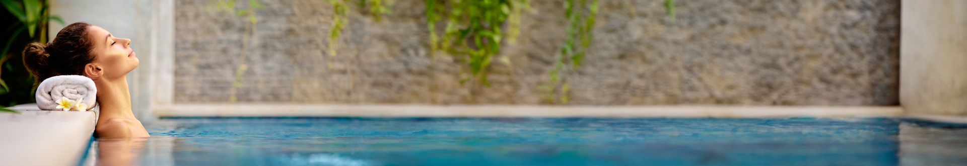 Person entspannt im Spa-Pool mit weitem Blick auf die moderne Wellness-Architektur, klares Wasser und stilvolle Umgebung