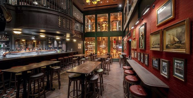 Gemütlicher Pub ‚Masters of the Sea‘ auf der MSC World America mit dunklem Holzinterieur, Barbereich und maritimer Wanddekoration