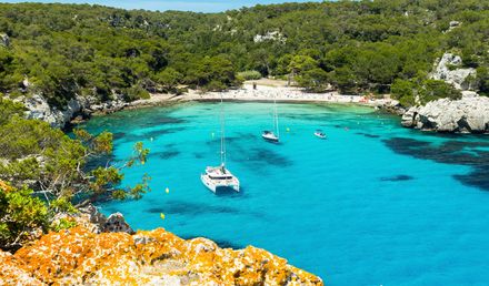 Cala Macarella auf Menorca in Spanien mit türkisfarbener Bucht, Segelbooten und Pinienwald
