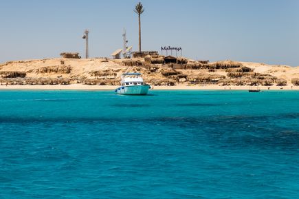 Boot vor der Sandinsel Mahmya mit Sonnenschirmen und 'Mahmya'-Schriftzug am Strand