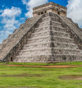 Große steinerne Pyramide mit breiten Stufen und flachem Tempelbau an der Spitze unter blauem Himmel