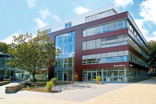 Außenansicht von Gebäude 2 bei schauinsland-reisen mit moderner Büroarchitektur, großflächigen Fenstern, Reisebüro im Erdgeschoss und Umgebung mit Bäumen