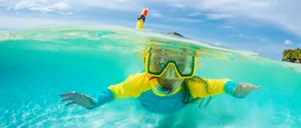 Kind mit Schnorchel und Maske schwimmt im klaren türkisfarbenen Meer