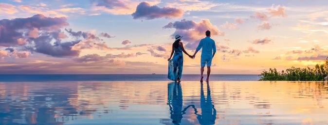 Paar am Infinity-Pool während des Sonnenuntergangs im Abendlicht 