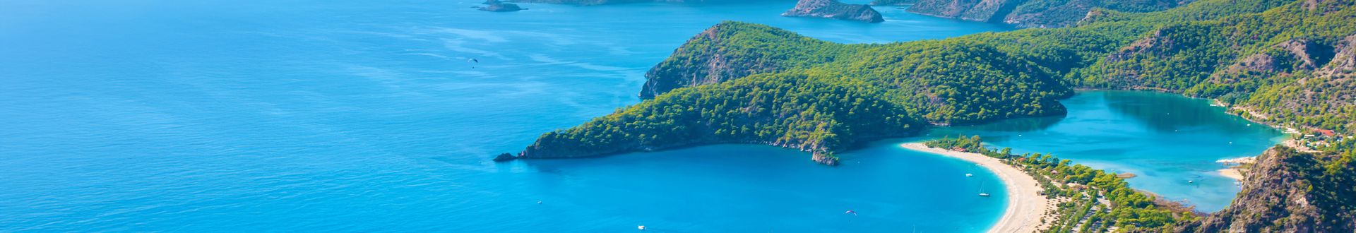 Panoramablick auf den Ölüdeniz-Strand mit der türkisfarbenen Lagune, dicht bewaldeten Hügeln und der weitläufigen Küstenlinie