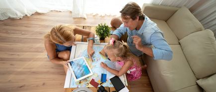 Familie mit Kind plant Urlaub zu Hause mit Weltkarte und Tablet