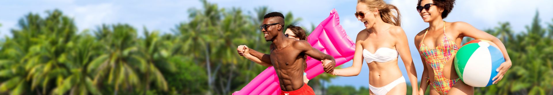 Mehrere Personen in Badekleidung laufen, halten einen bunten Strandball und eine pinke Luftmatratze, während hinter ihnen grüne Palmen sommerliches Urlaubsfeeling vermitteln