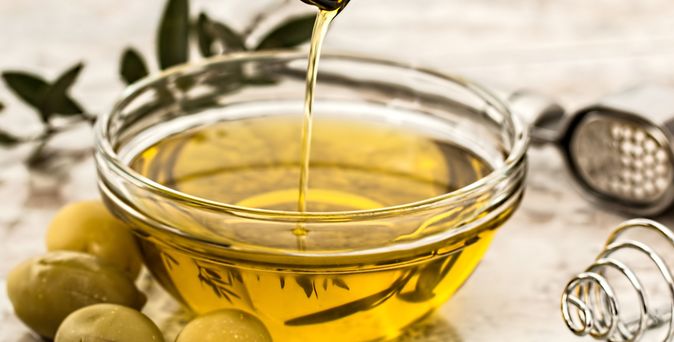 Schale aus Glas wird mit Olivenöl befüllt
