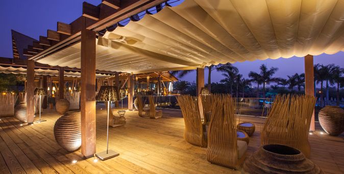 Stimmungsvoll beleuchteter Outdoor‑Loungebereich aus Holz mit gemütlichen Sitzbereichen im Lopesan Baobab Resort