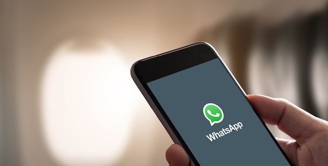 Hand hält Smartphone mit geöffneter WhatsApp-App auf dem Bildschirm