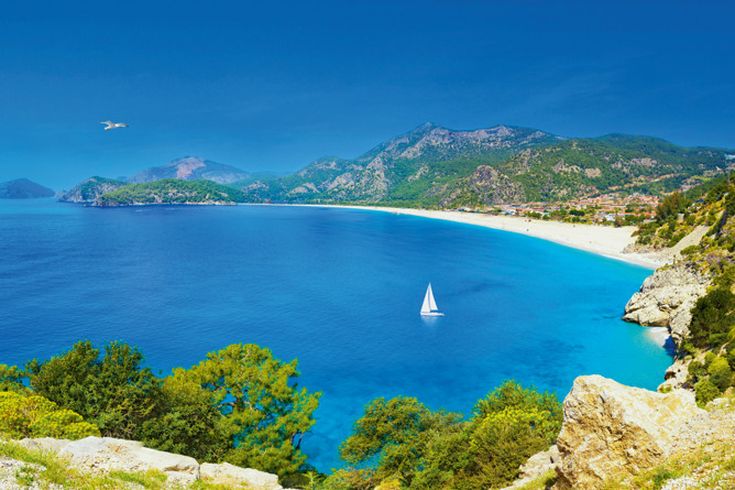 Panoramablick auf die berühmte Bucht von Ölüdeniz bei Fethiye mit intensiv blauem Meer, Sandstrand und grünen Bergen