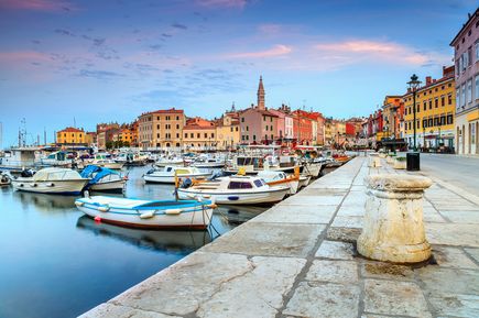 Hafen und Altstadt von Rovinj in Istrien, Kroatien, mit bunten Häusern, Kirche, Booten und Promenade bei ruhigem Wasser und Abendlicht