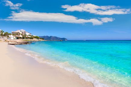 Strand von Cala Millor auf Mallorca mit hellem Sand, türkisblauem Wasser und Promenade mit Hotels im Hintergrund