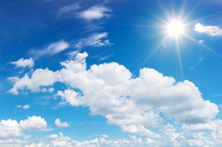 Blauer Himmel mit strahlender Sonne und weißen Wolken an einem Sommertag