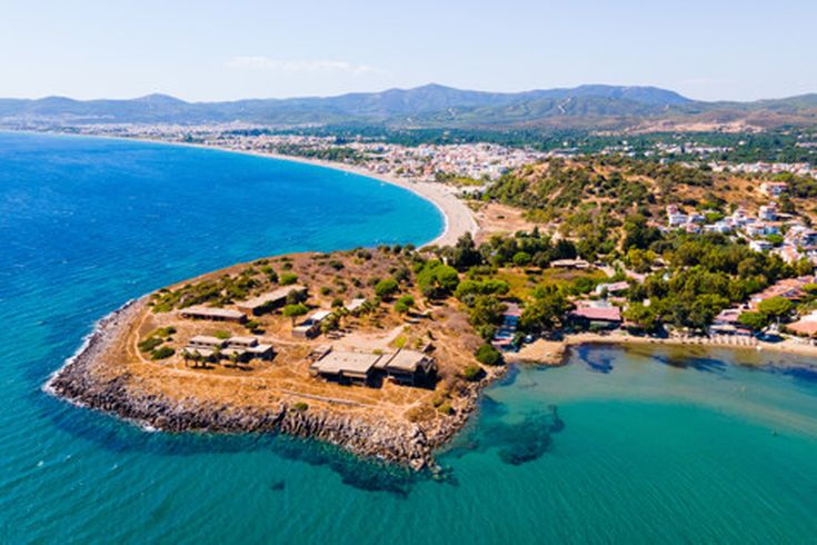 Luftaufnahme von Seferihisar bei Izmir in der Türkei mit Küstenlinie, türkisblauem Meer, grünen Hügeln und Häusern entlang des Strandes