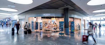 Flughafen Stuttgart Innenbereich mit Shop „Jet Setter Travel“, Reisende mit Gepäck im Terminal und moderner Ladenfläche