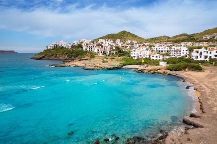 Der Küstenort Fornells auf Menorca liegt an einer geschützten Bucht mit weißen Häusern und klarem, blauem Meer