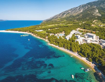 Luftaufnahme des Bretanide Sport & Wellness Resorts an der kroatischen Küste mit Strand, Pinienwald und Bergen im Hintergrund