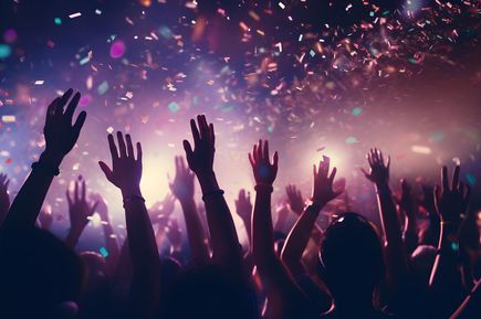 Menschen feiern ausgelassen in einem Club, heben die Hände in die Luft, während buntes Konfetti im Scheinwerferlicht herabfällt