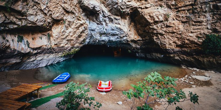 Eingang der Altınbeşik-Höhle in der Türkei mit unterirdischem See, Felswänden und kleinen Booten am Ufer