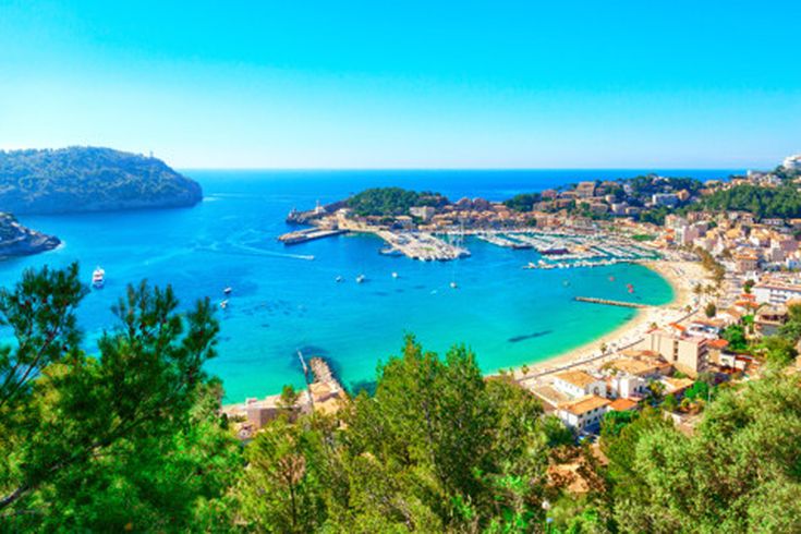 Panoramablick auf den Hafen von Port de Sóller auf Mallorca mit Strand, Promenade und Yachthafen, umgeben von grünen Hügeln