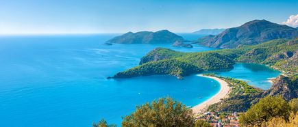 Panoramablick auf die türkisfarbene Lagune von Ölüdeniz an der türkischen Ägäis, umgeben von grünen Bergen, geschwungenem Sandstrand und ruhigem, klaren Meer