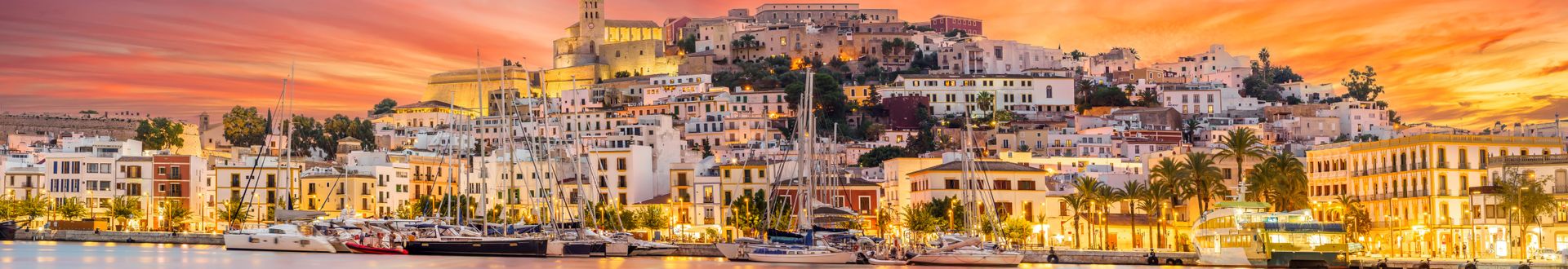 Abendstimmung in Ibiza-Stadt mit beleuchteten Häusern, Yachthafen und der Altstadt Dalt Vila im Sonnenuntergang