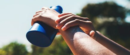 Eine Hand trägt Sonnencreme auf den Unterarm auf, Sonnenschutz im Freien bei warmem Wetter