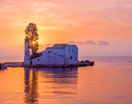 Kirchengebäude auf kleiner Insel bei Sonnenuntergang mit orangefarbenem Himmel und ruhigem Wasser