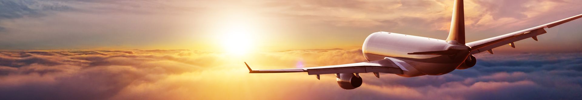 Passagierflugzeug fliegt in Richtung Sonnenuntergang über einer geschlossenen Wolkendecke; stimmungsvolle Himmelsszene im warmen Licht