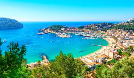 Panoramablick auf den Hafen von Port de Sóller auf Mallorca mit türkisblauem Meer, Yachthafen und umliegenden Hügeln bei strahlend blauem Himmel