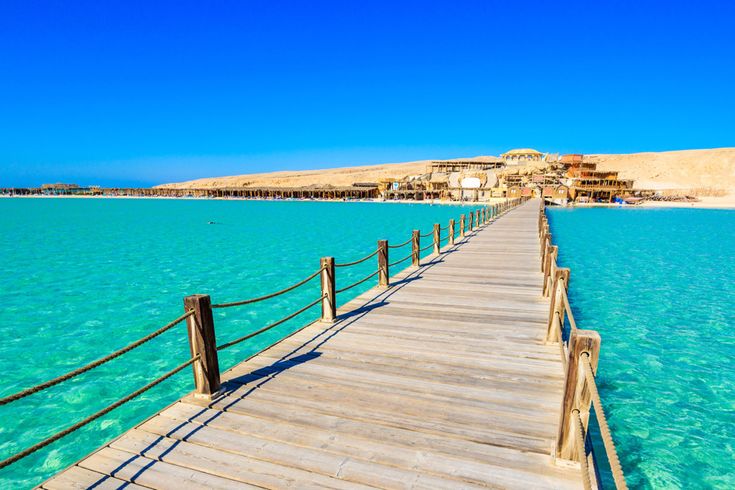 Holzsteg über türkisfarbenes Meer, der zur Orange Bay Strand- und Lagunenanlage führt